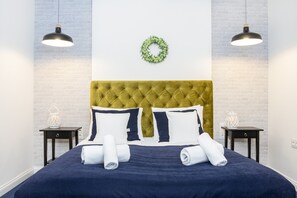 Relax in a serene space with a tufted headboard, dark blue bedspread, and intricately designed lanterns.