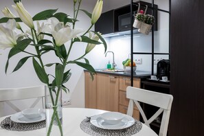 Enjoy meals at the dining table, surrounded by a vase with fresh greenery and a fruit bowl.