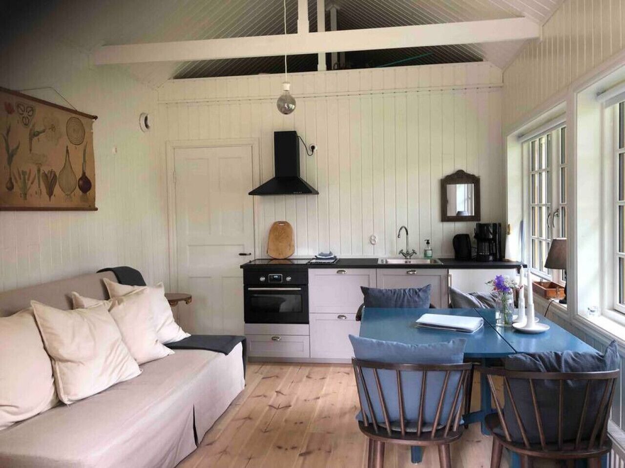 Ett kompakt kök med en matplats, en vit soffa och ett bord med stolar.