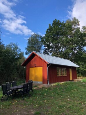 A red building with a yellow garage door, surrounded by trees and a grassy area.