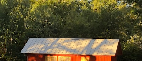Un petit bâtiment d’un seul étage, doté d’un toit métallique incliné et entouré d’arbres denses.