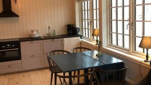 Eine Küche mit Esstisch, Stühlen, Herd und einem Fenster mit vielen Glasscheiben.