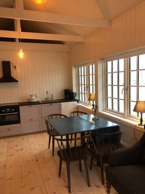 A kitchen with a dining table, chairs, a stove, and a window with multiple panes.