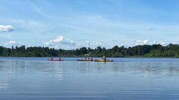 Ein ruhiger See mit Kajaks und Kanus, umgeben von Bäumen und einem klaren Himmel.