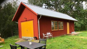 Ein rotes Backsteinhaus mit gelbem Tor, ein Tisch mit Stühlen und ein kleiner Gartenbereich.