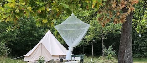 A tent, a canopy, and a table with chairs in a natural setting.