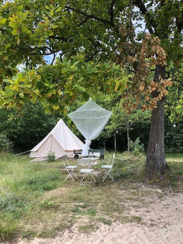 A tent, a canopy, and a table with chairs in a natural setting.