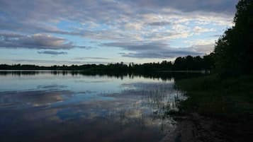 Un lac paisible, bordé d’une forêt et surplombé d’un ciel nuageux.