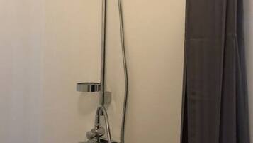 A shower with a handheld showerhead, a wall-mounted control panel, and a curtain.