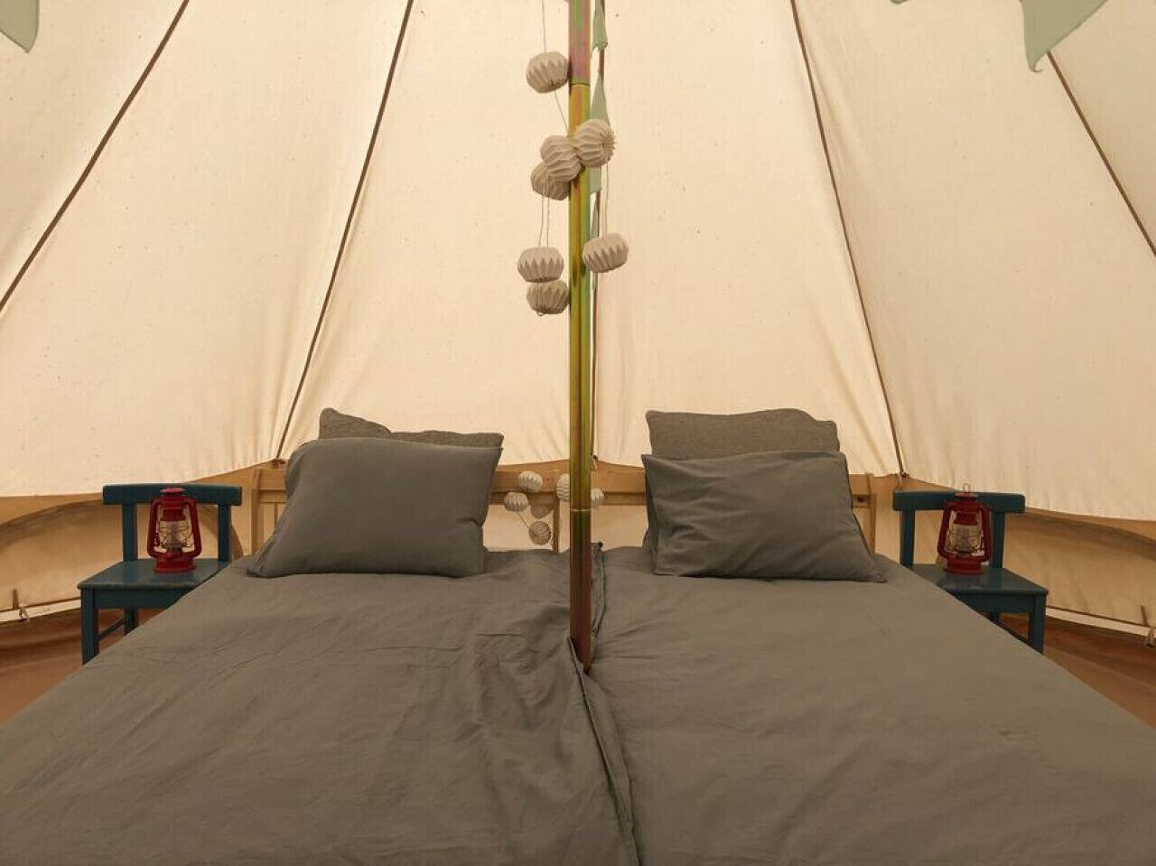 Une tente équipée d’un lit, d’oreillers et de deux lampes de chevet.