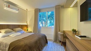 Quarto de hotel moderno com uma cama grande, uma escrivaninha e uma televisão na parede.