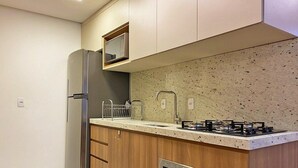 Cozinha compacta com geladeira embutida, micro-ondas, fogão a gás e forno.