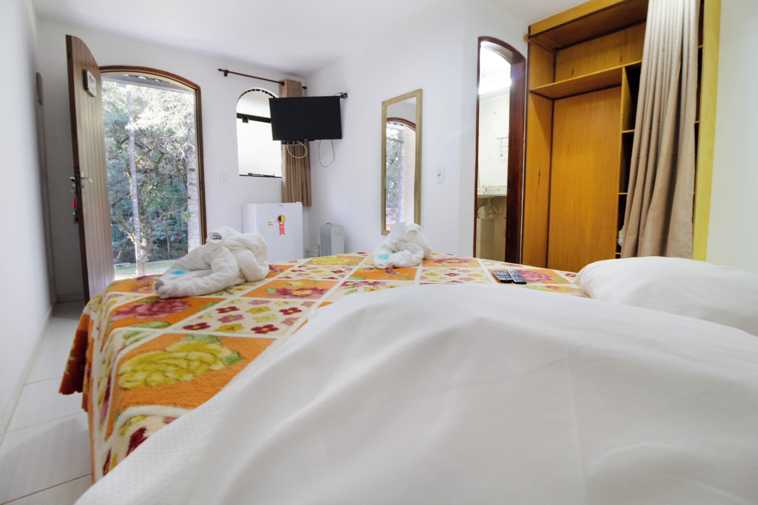 Een hotelkamer met een bed, een televisie, een kast en een raam met gordijnen.