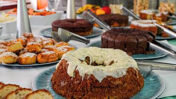 Un bufé con diversos postres, incluyendo pasteles y bollería.