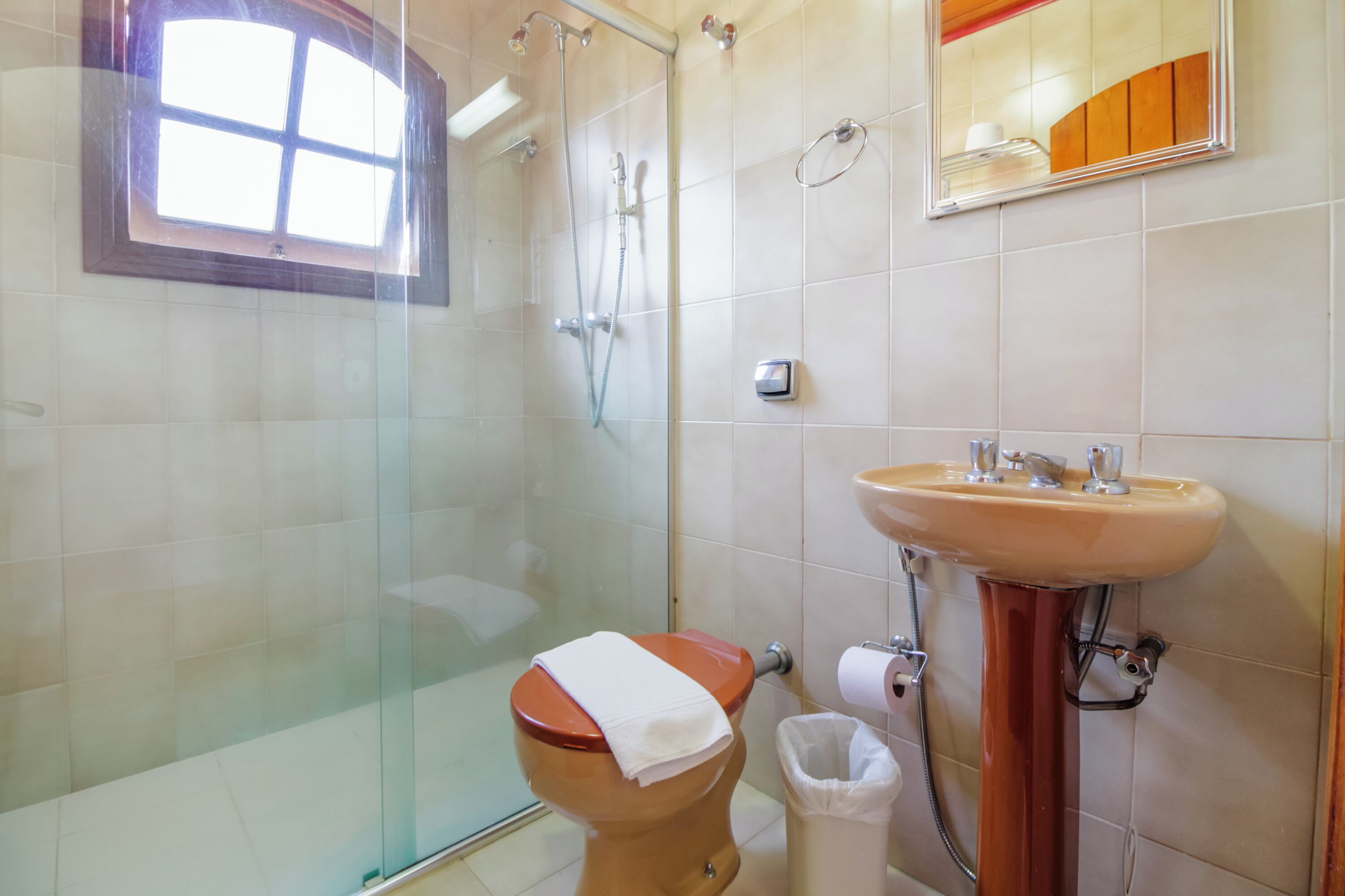 Ein Badezimmer mit Toilette, Dusche, Waschbecken und einem Fenster.
