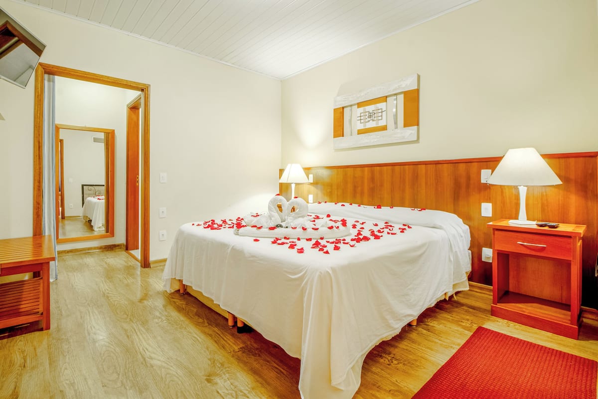 Ein Hotelzimmer mit einem großen Bett, einem Holzkopfbrett, zwei Nachttischlampen, einem Nachttisch aus Holz und einem roten Teppich.