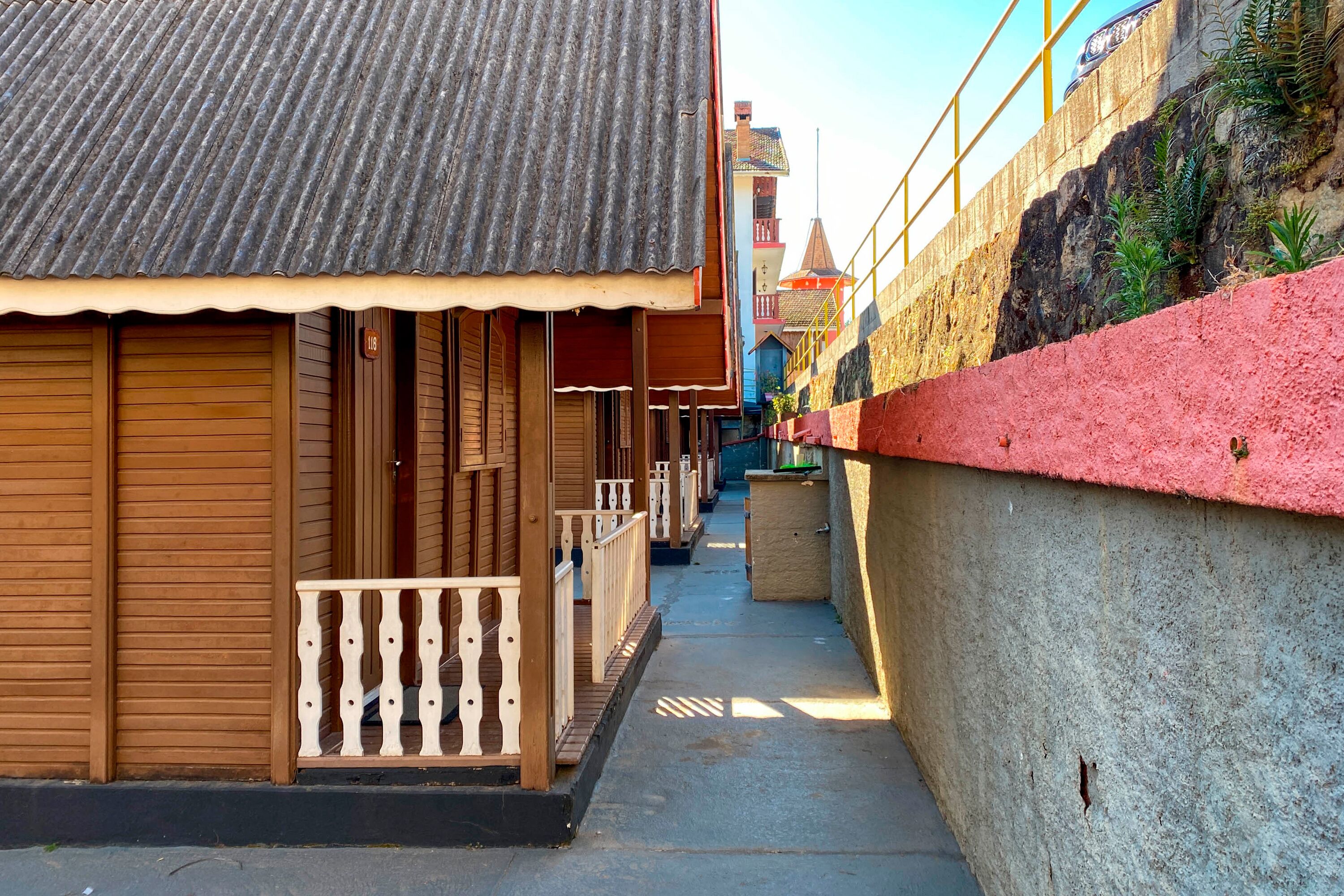 Un estrecho callejón con edificios de madera, un muro rojo y un tejado de tejas.