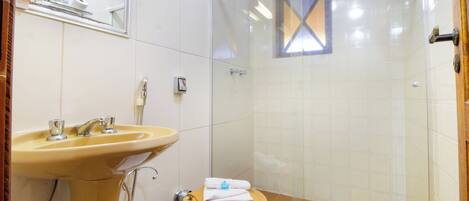 A bathroom with a sink, toilet, and glass shower enclosure.