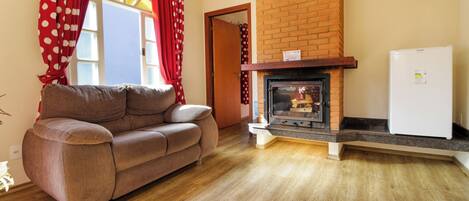 A living room with a sofa, fireplace, and a refrigerator.
