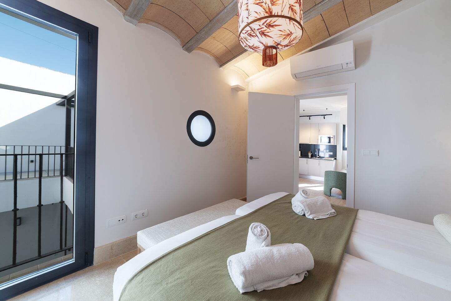 Ein modernes Hotelzimmer mit einem großen Bett, einem runden Spiegel, einem Balkon und Blick zum Himmel.