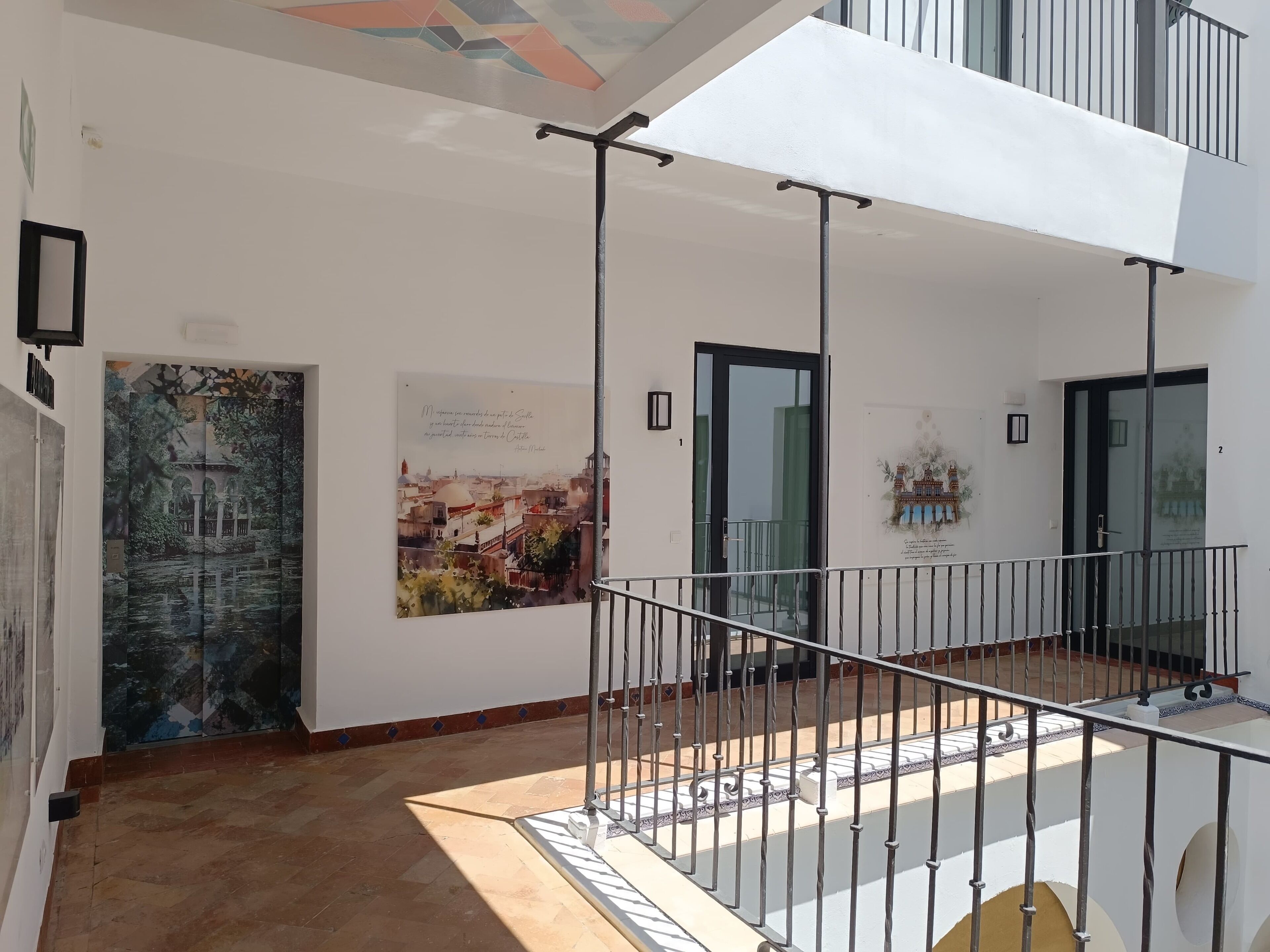A spacious indoor area with a tiled floor, a balcony with a metal railing, and a door leading to another room.
