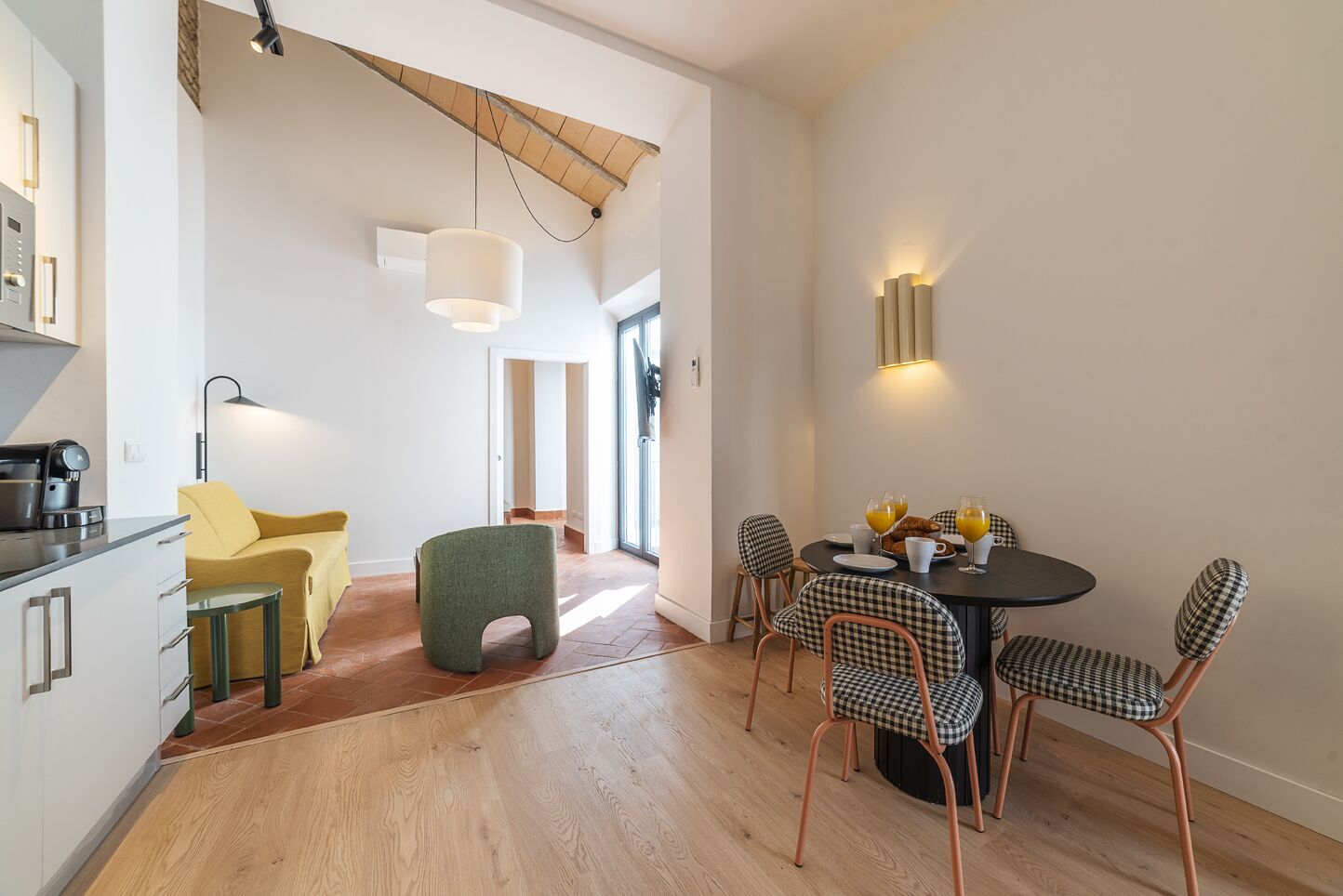 A modern kitchen with a dining area featuring a round table and checkered chairs.