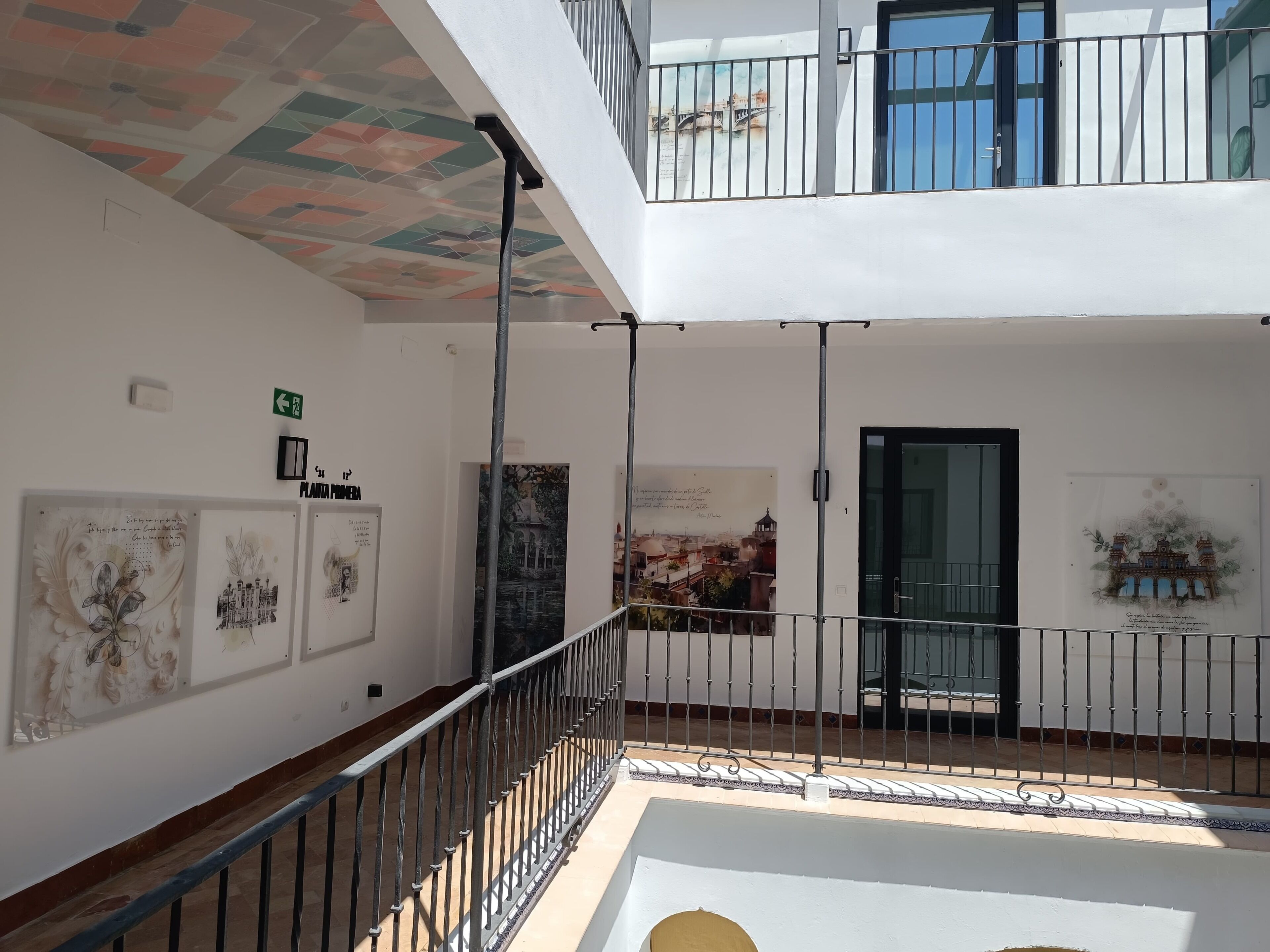 A multi-level atrium with artwork on the walls, a staircase, and a balcony with a railing.