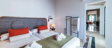 Una habitación de hotel con una cama grande, dos almohadas, un plaid verde y un perchero.