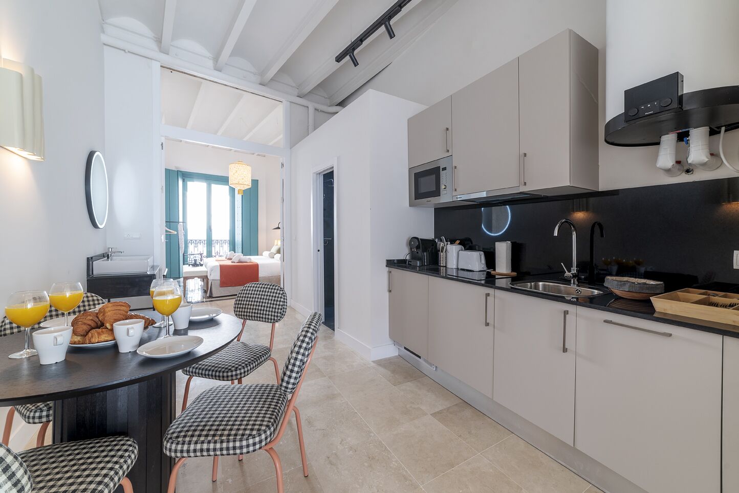 A modern kitchen with a dining area, featuring a breakfast setup with croissants and orange juice.