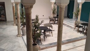 A spacious courtyard with marble flooring, columns, and outdoor seating. - Slow Suites Salvador (Seville)