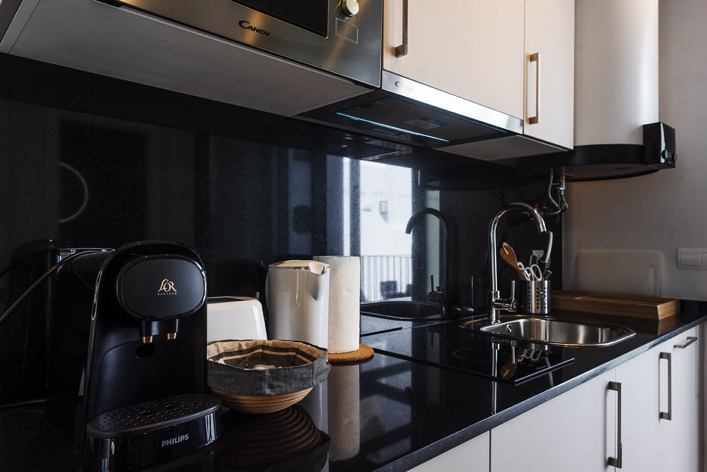 A modern kitchen with a black countertop, stainless steel appliances, and white cabinets.