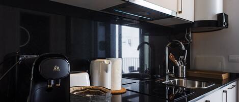 A modern kitchen with a black countertop, stainless steel appliances, and white cabinets.