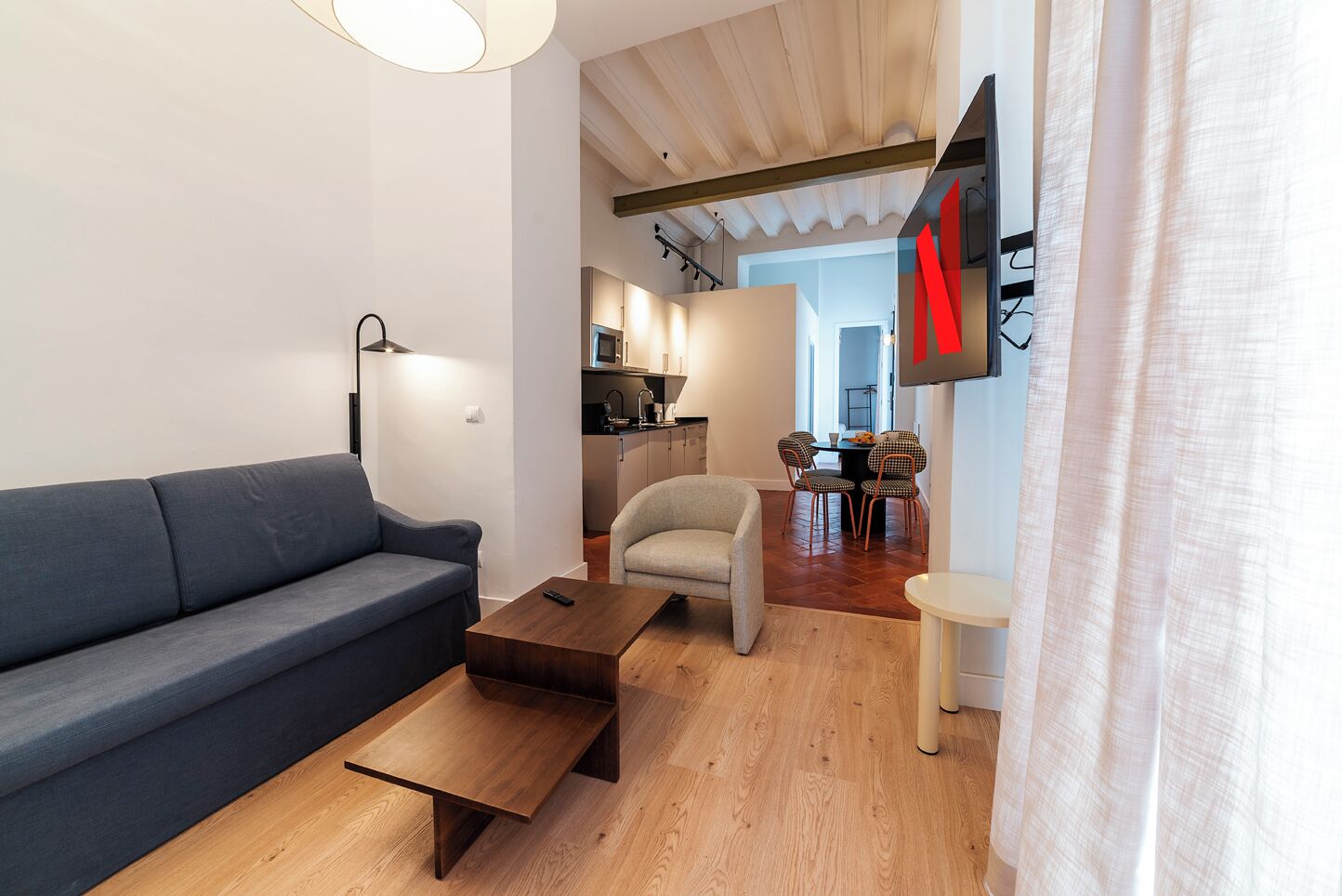 A modern living room with a sofa, coffee table, and a TV mounted on the wall.