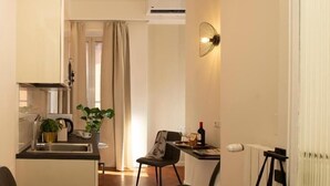 Un espacio habitable compacto con kitchenette, comedor y zona de estar.