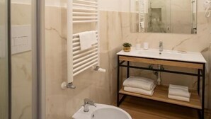 Un baño con cabina de ducha de vidrio, un lavamanos blanco con espejo y un bidé.