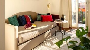 Una sala de estar moderna con un sofá, una mesita redonda y un amplio ventanal con cortinas.