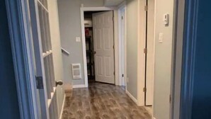 A hallway with wooden flooring, white walls, and a ceiling light fixture. - Cozy basement apartment suite, beautiful Paradise! (Paradise)