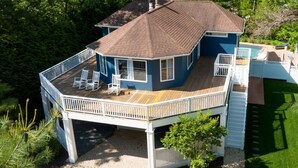 A two-story house with a deck, a swimming pool, and a well-maintained lawn.