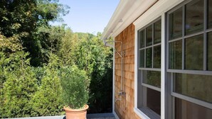 A wooden exterior wall with a window, a potted plant, and a metal shower structure. - Heated Pool Grill Breakwater by Rovetravel (Sag Harbor)