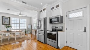 A modern kitchen with white cabinetry, stainless steel appliances, and hardwood floors. - Heated Pool Beach Miramar Villa by Rovetravel (West Palm Beach)