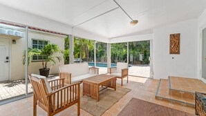 A spacious patio with a wooden table and chairs, a potted plant, and a view of a swimming pool. - Heated Pool Beach Miramar Villa by Rovetravel (West Palm Beach)