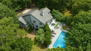 An aerial view of a house with a swimming pool surrounded by dense trees. - Meadowood Manor by Rovetravel Heated Pool (Sag Harbor)
