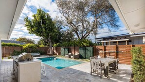 Ein Garten mit Swimmingpool, Grill und Gartenmöbeln.