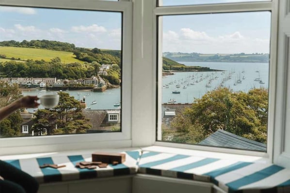 A bay view from a window with a view of boats and a green landscape.