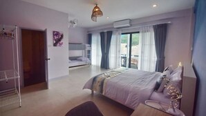 Une chambre avec un lit, un bureau et une chaise. Il y a une fenêtre avec des rideaux, une porte et une étagère fixée au mur.