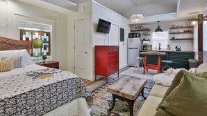Ett kompakt bostadsutrymme med en säng, soffa, litet kök och en matplats.