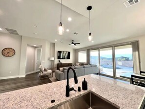 A modern kitchen with granite countertops, a stainless steel sink, and pendant lighting.