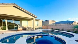 Ett modernt hus med en swimmingpool, utomhusmöbler och en täckt uteplats.