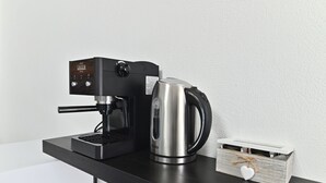 Una cafetera y un hervidor sobre una encimera negra.