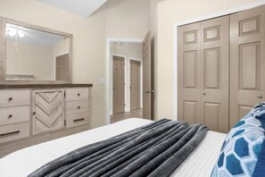 A bedroom with a bed, a dresser, a mirror, and a door. - Private Pool, 4 Miles to Disney-6BR / 4 baths Home (Kissimmee)
